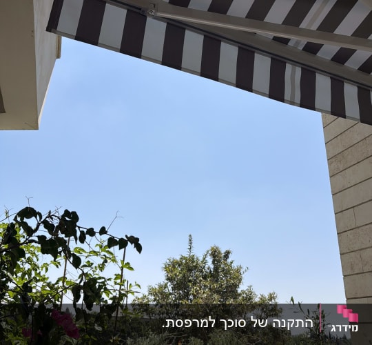 סוכך זרועות מותקן מעל מרפסת עם צמחים